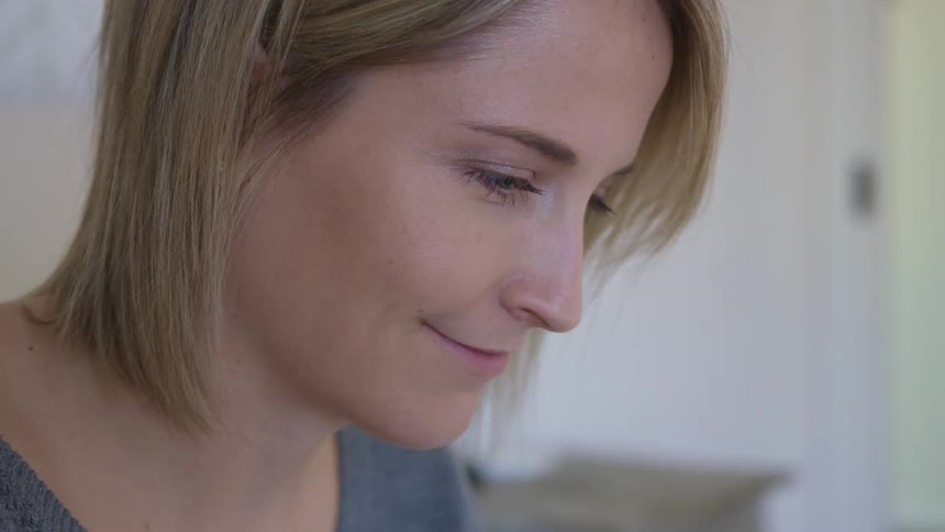 Side view of a blonde woman looking down and smiling slightly