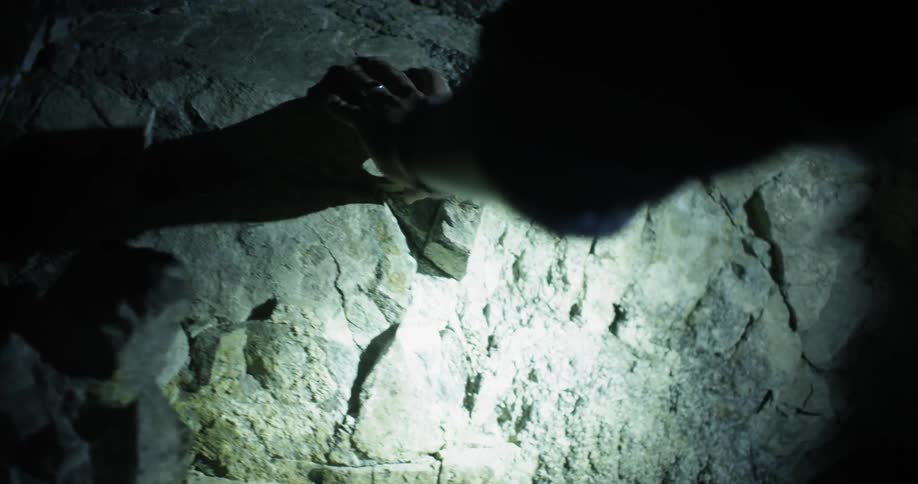 A man explores a cave with a flashlight