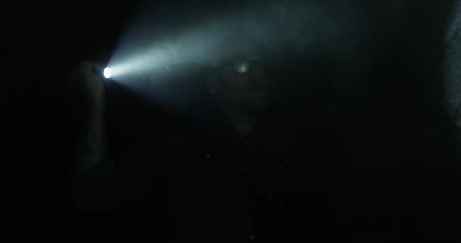 A man shining a flashlight on a cave wall