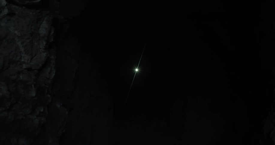 A single light flashes in a dark cave