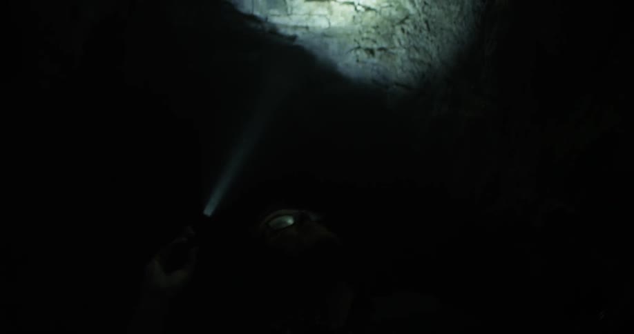 A man holds a flashlight in a cave at night
