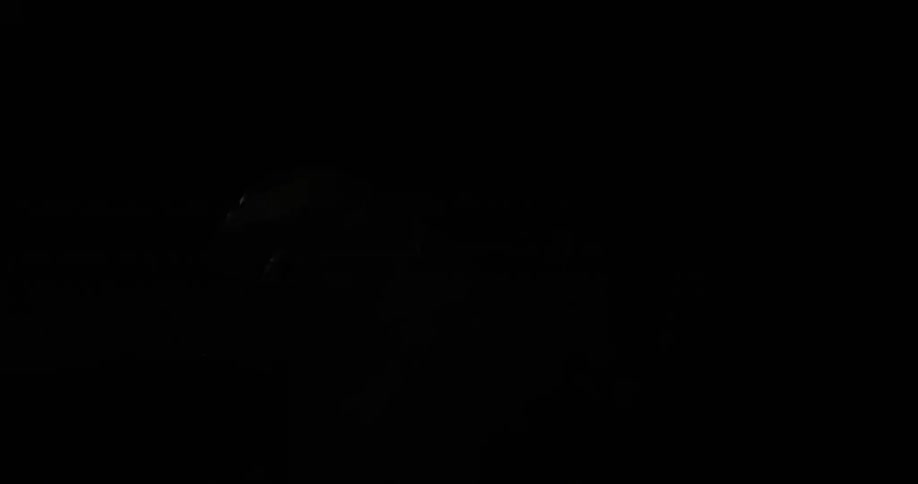 A person using only a flashlight walks through a cave
