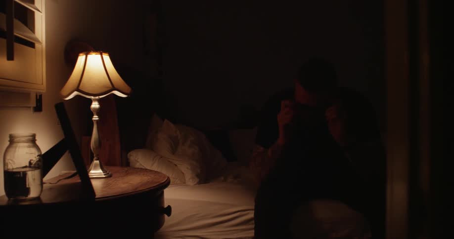 A man turns on a lamp and sits up in bed