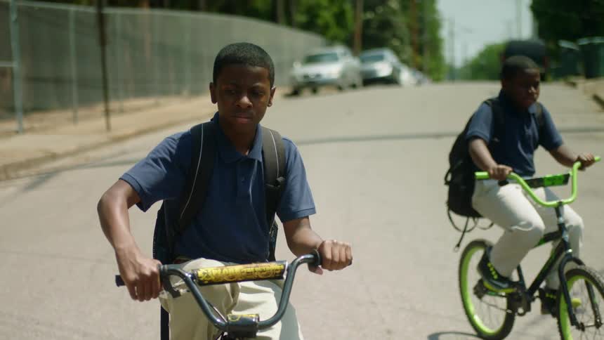 Two children ride their bicycles down the street