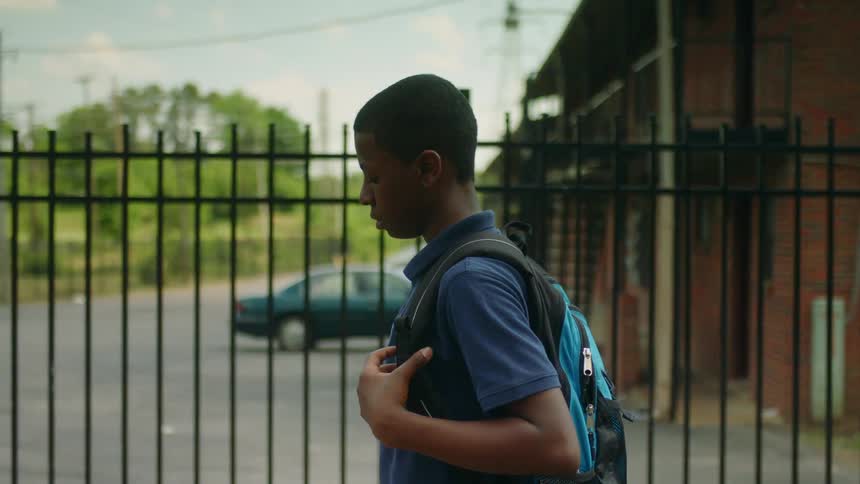 Young man wearing a backpack dribbles a basketball while walking on the streets of a neighborhood