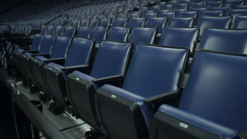 Rows of blue reclining chairs on a stadium at night