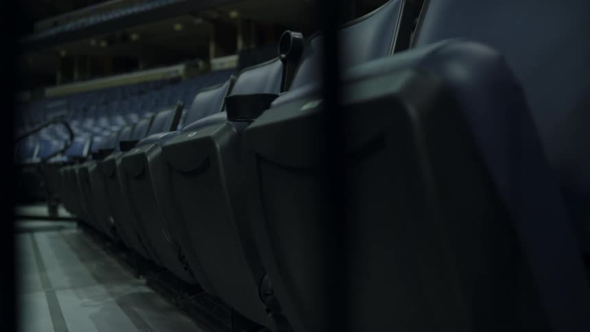 Rows of blue reclining seats in a stadium at night