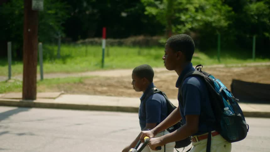 Two black young males walking together wearing backpacks