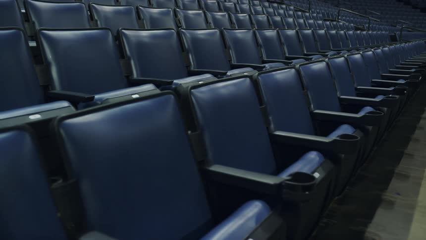 Rows of blue reclining chairs in a stadium at night