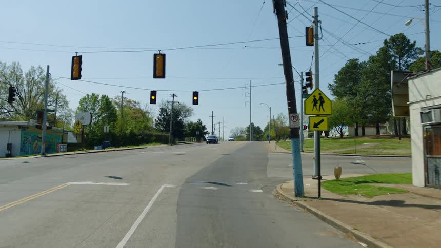A car travels through a small town on a clear summer day