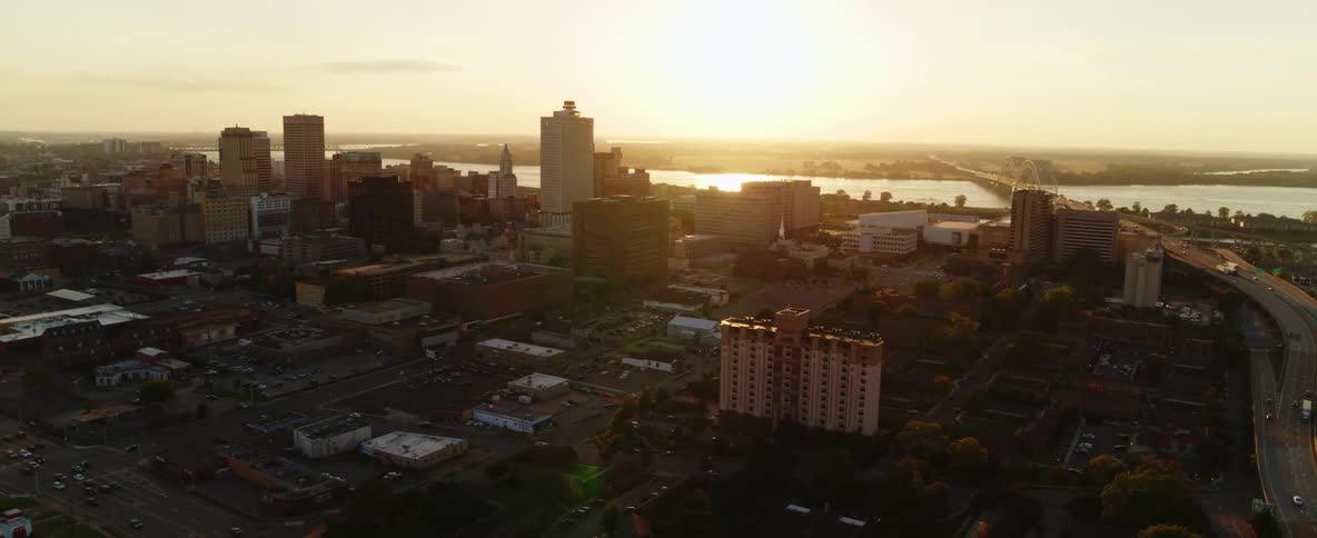 The low sun shines down on a metropolis next to a river