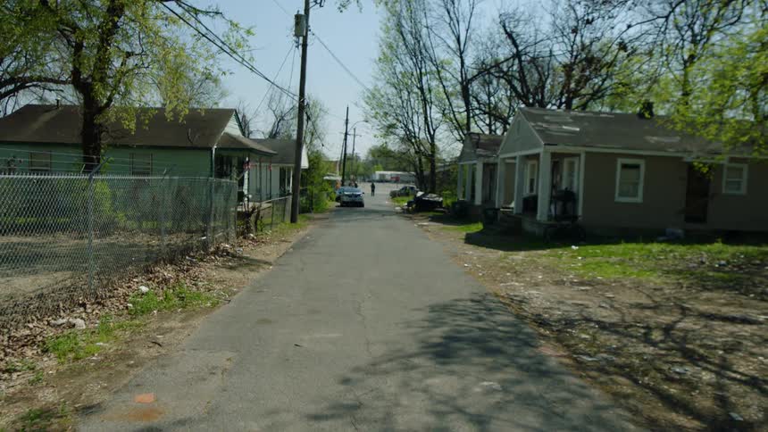A neighborhood street with cars parked on it and one person walking