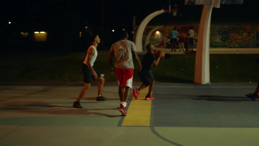 A group of black males playing basketball at night