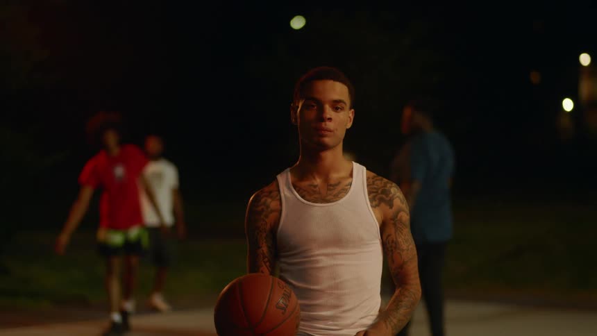 A teenage boys starts dribbling a basketball as he prepares to play with friends