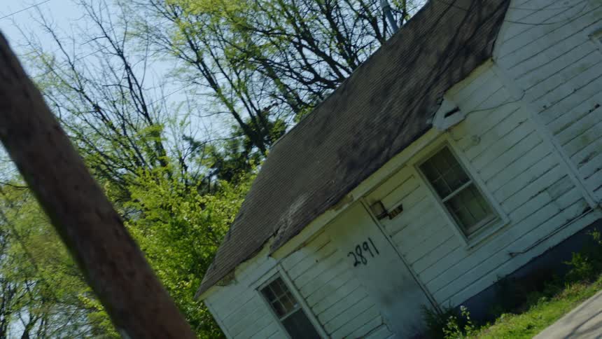 Crooked footage of abandoned homes in a neighborhood at day