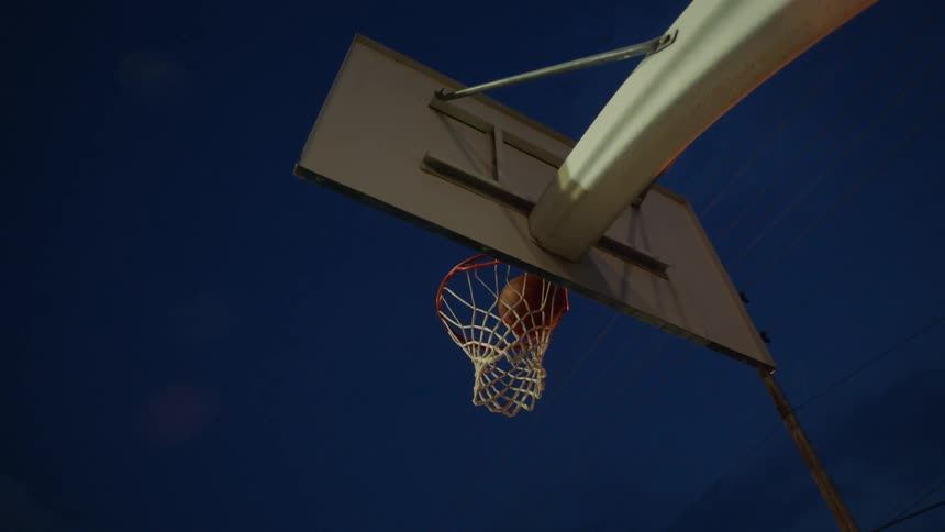 A teenage boys jumps and dunks a basketball in the hoop