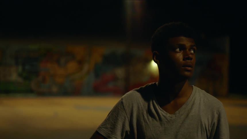 Man stands on basketball court looking around while others play basketball in background