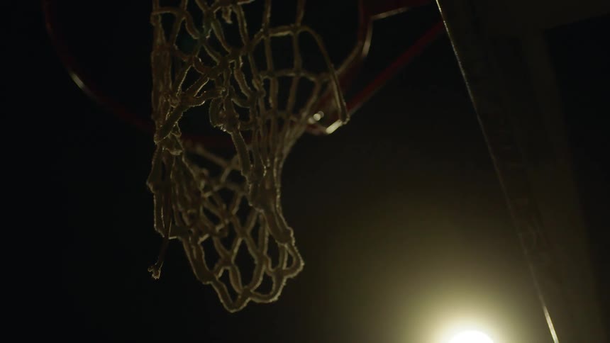 A light shining down on a net on a basketball hoop