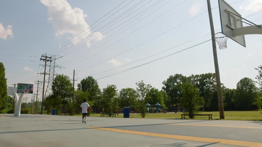 Child walking on a basketball court holding a basketball