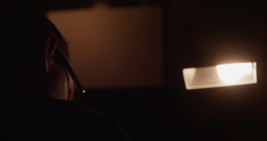 A man works at a desk in a dark room
