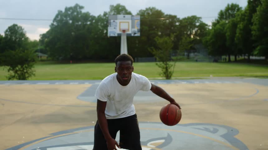 Man dribbles basketball on court in park then runs