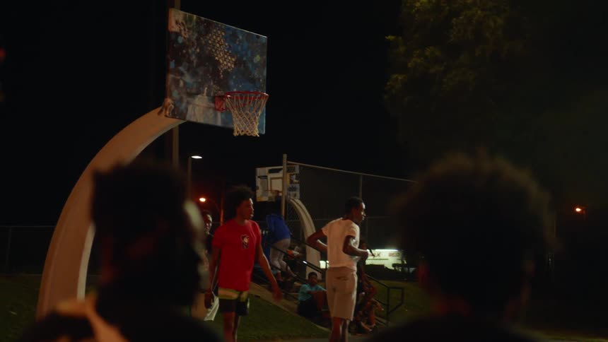 A group of teenage boys playing basketball on an outdoor court