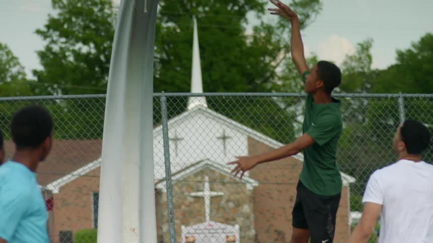 A group of teenage boys play basketball at a public park