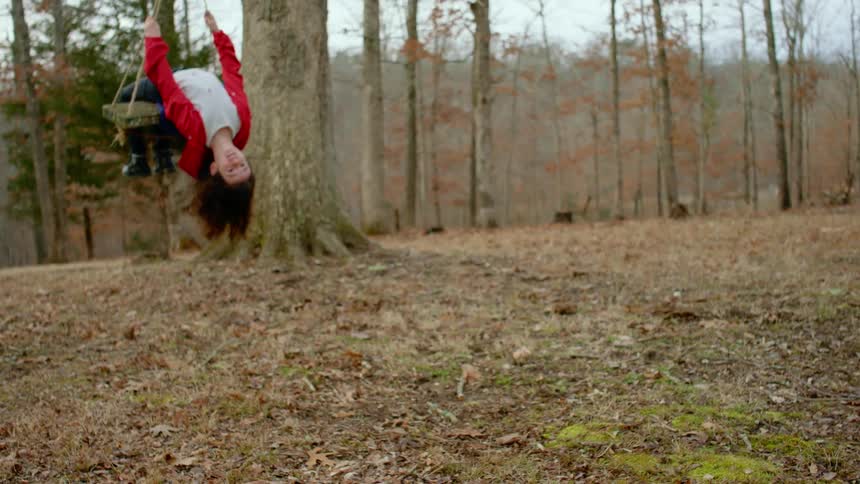A girls leans back as she swings outside