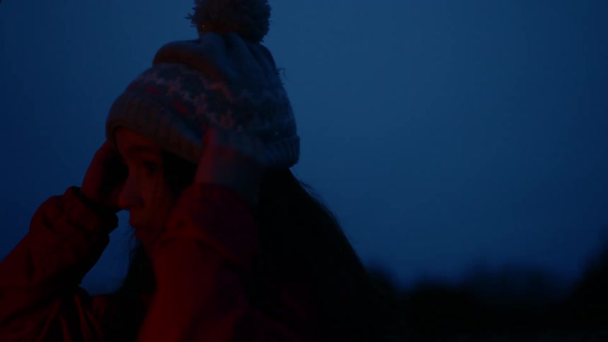 Side view of a teenage girl wearing a beanie at night