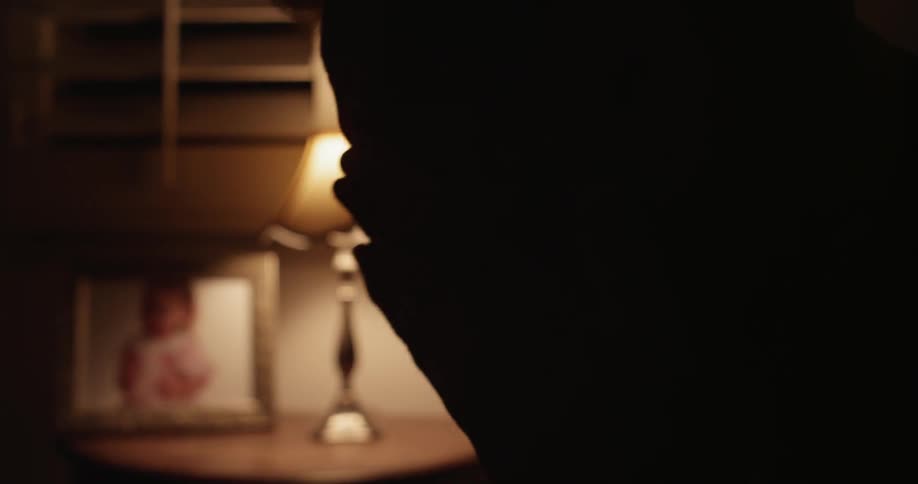 A man turns on a light and puts his glasses on