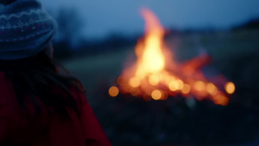 A little girl looks at a big bonfire