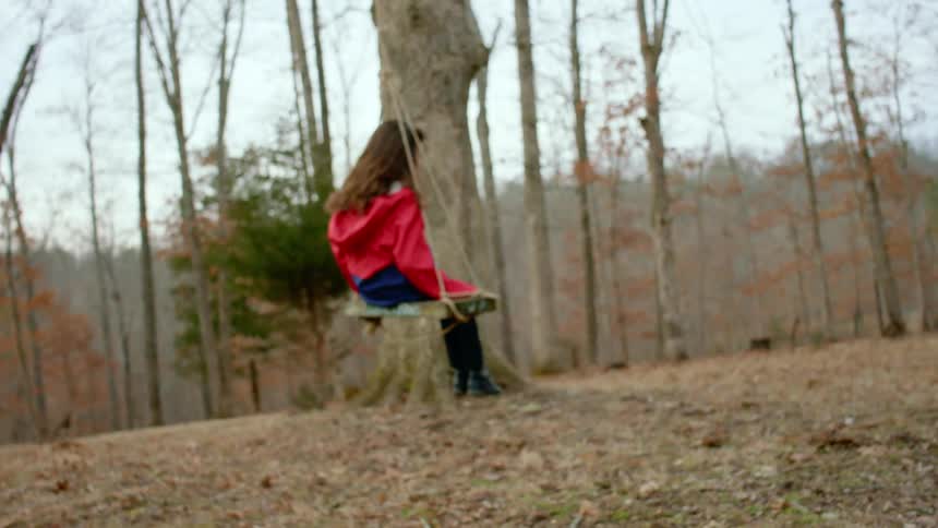 A young girl swinging in a wooded area