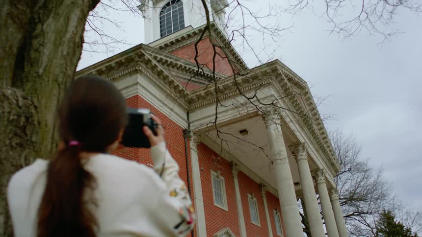 A young girl takes pictures of a building with her camera