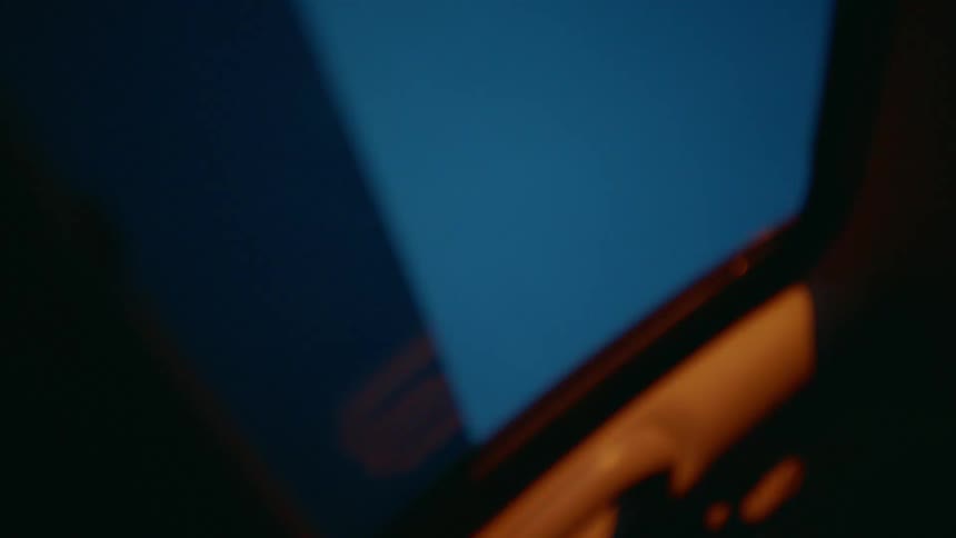 A car drives beneath a glowing street lamp at night