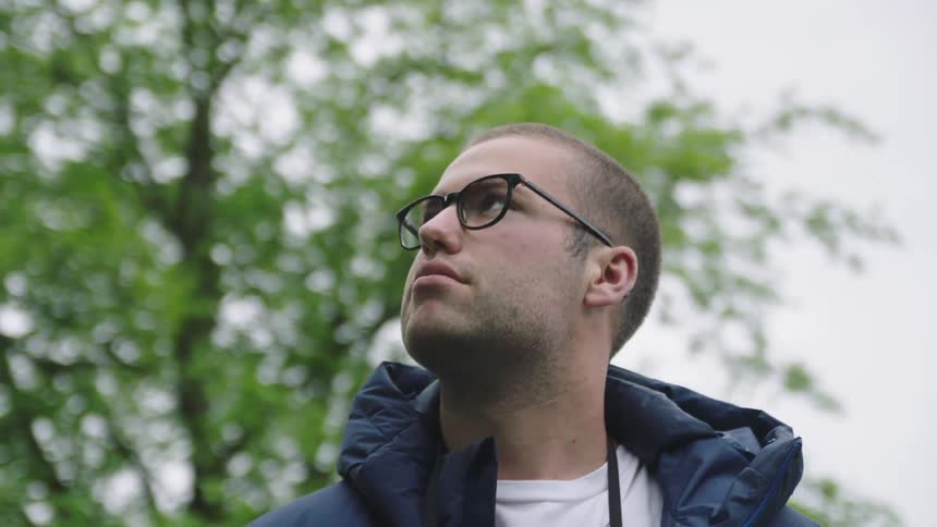 A man wearing glasses is standing outdoors