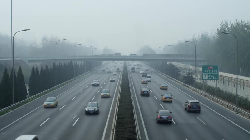 A highway with vehicles with trees the sky and clouds in the background
