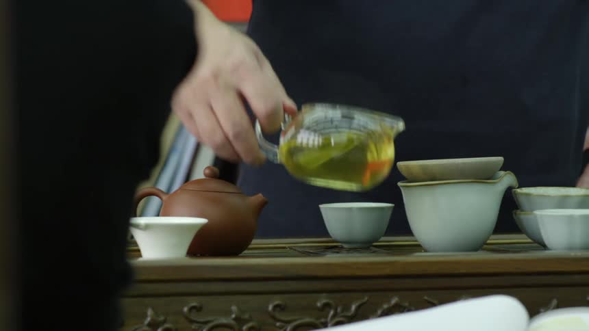 Two women look at a book as a man makes tea in a restaurant