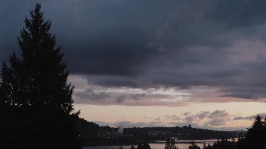 Dark clouds over a landscape with a lake and trees and a skyline in the distance