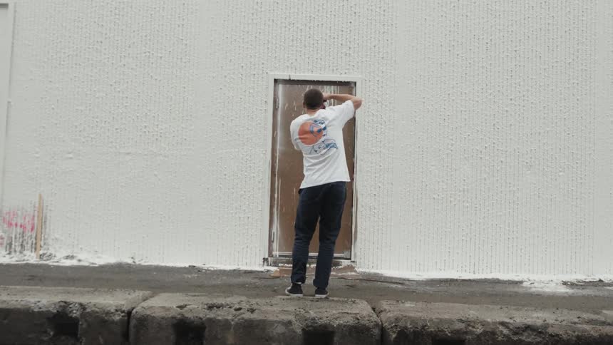 A man takes an up close photo of a brown doorway at a large white building