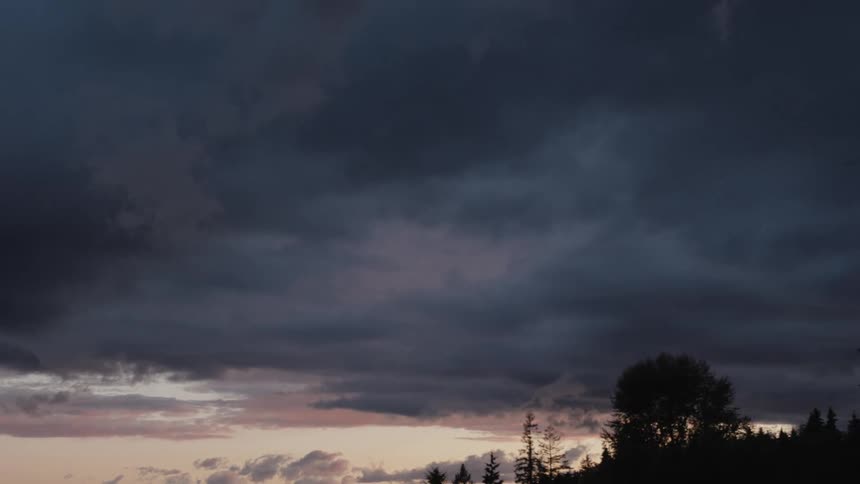 Dark clouds loom in the sky over a hill in the evening