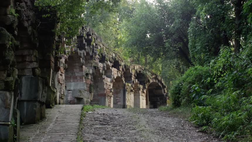 A brick tunnel along side a path and trees
