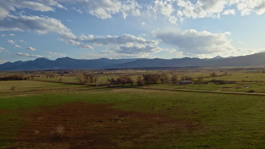 An aerial view of a field and distant mountains in the daytime
