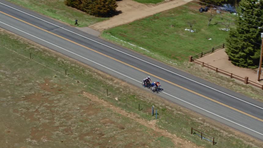 Aerial view of a group of cyclist cycling a country road in the countryside