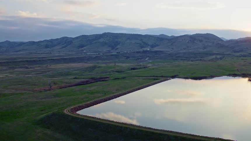 An aerial view of a reservoir surrounded by mountains on a summer morning
