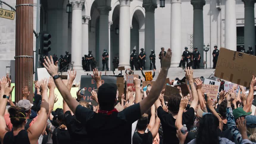 Police stand watch as a crowd of protesters hold signs