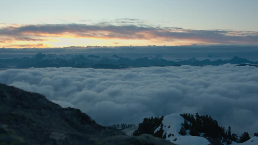 A sea of clouds hiding the land below a mountain peak from view