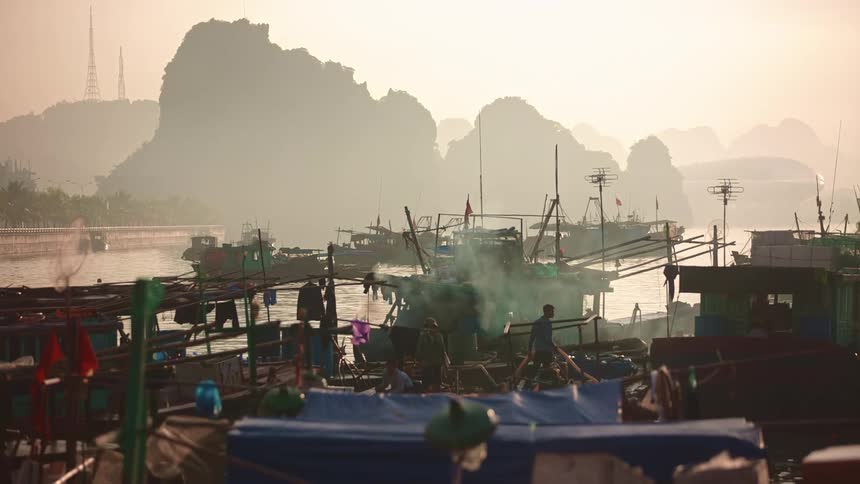 Sun turns sky and fog pink as people on boats maneuver around each other on the water