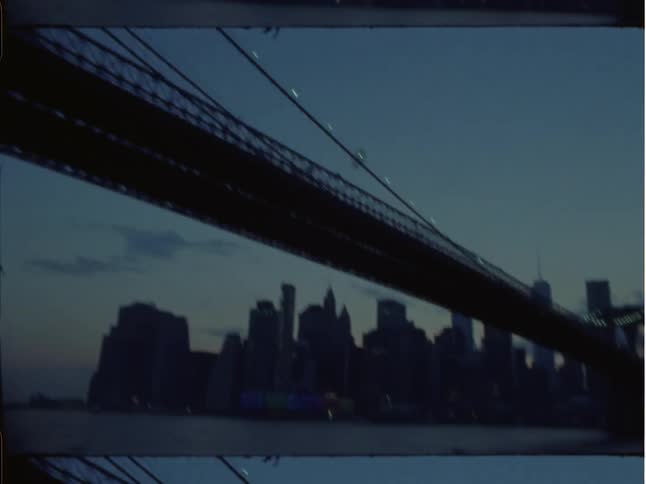 A silhouetted city bridge and skyscrapers at dusk