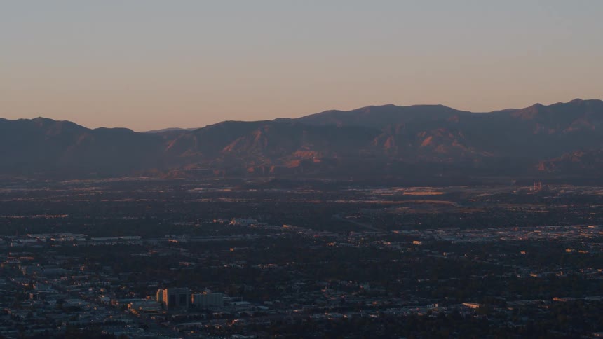 Aerial view of a small city in the plains near a mountain range at sunset