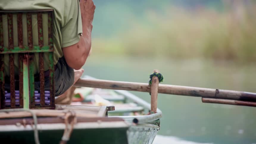 Man uses his foot to paddle a boat in the lake